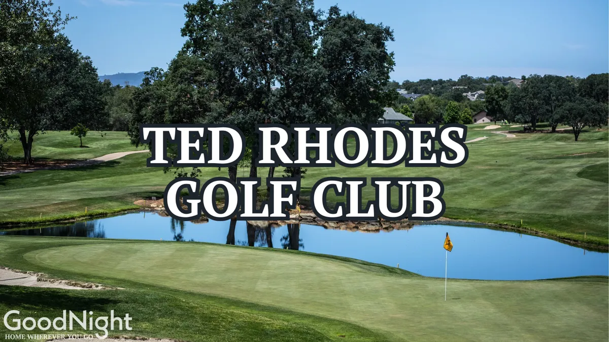A serene view of a lush golf course with a prominent water feature, well-maintained greenery, and a visible golf flag, suggesting an inviting environment for both golfing and relaxation. The natural surroundings and open sky set a tranquil, leisurely mood.