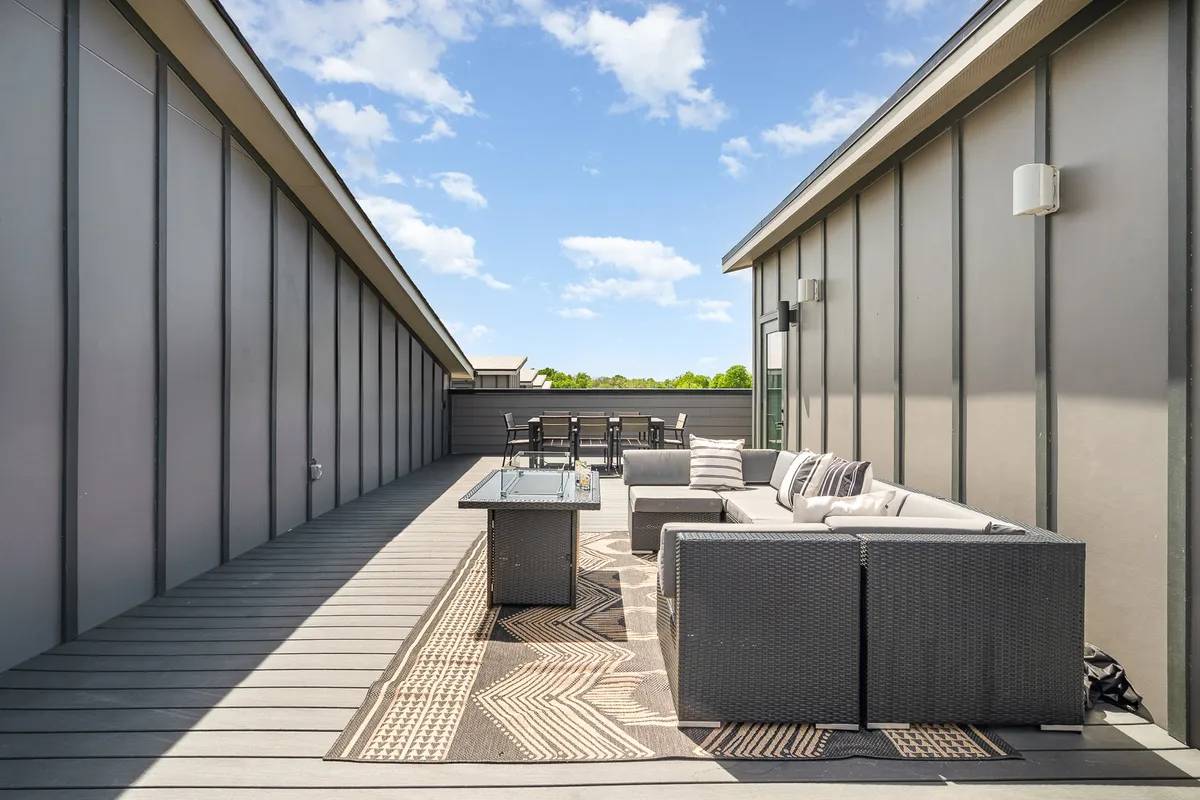 An inviting outdoor rooftop setting with a dining table and seating area atop a decorative rug. The space is styled for al fresco meals or sunset gatherings, with an atmosphere of warmth and casual sophistication ideal for memorable rooftop experiences.