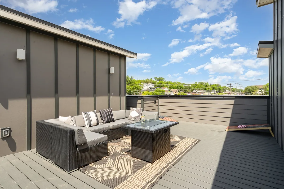 A rooftop lounge area with outdoor seating and a coffee table, set atop a decorative rug. The ambiance is intimate and inviting, ideal for relaxing with friends, enjoying drinks around the fire pit, or stargazing in the evening.